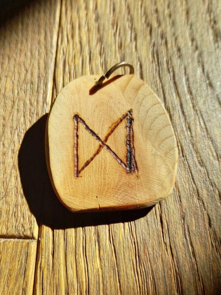 Le Rune significati e leggende. 
Ciondolo di legno con inciso la runa Dagaz
